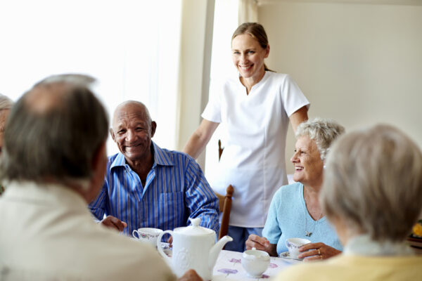 Seniors enjoying tea with care staff in cheerful atmosphere.