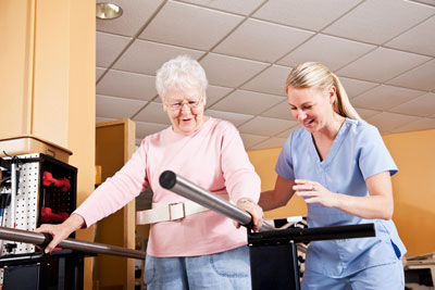 Elderly woman receiving assistance during rehabilitation therapy session.