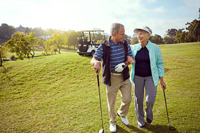 Elderly couple enjoying a walk on a golf course.
