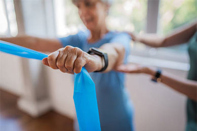 Older adult exercising with resistance band, assisted by another.