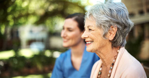 Two women smiling outdoors, one older and one younger.