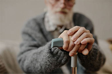 Elderly person resting hands on a cane, soft focus.