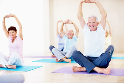 Seniors practicing yoga in a bright, spacious studio.