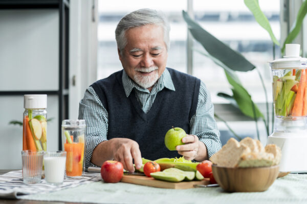 Asian elder senior male vlog teach cooking on mobile phone. Male old man vlogs, Old chef records a video tutorial on his phone about preparing heathy salad and infused water at home