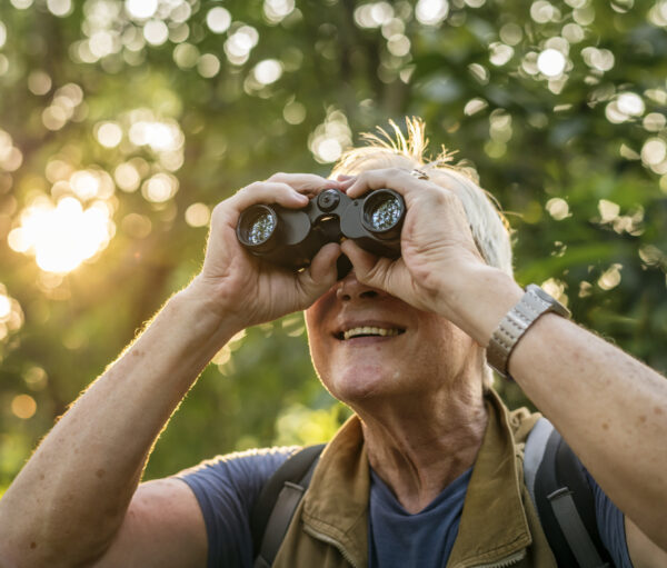 Elderly man watching birds with binoculars